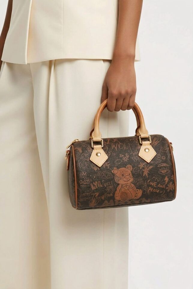 KÜÇÜK KAHVERENGİ AYICIK FİGÜRLÜ VE GRAFİKLİ EL KOL ÇANTASIDIR